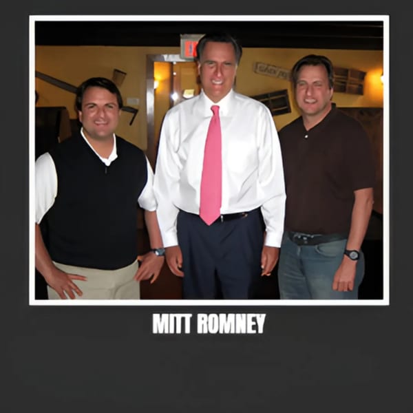 Mitt Romney in a white shirt and pink tie, flanked by two men, inside Bessinger's BBQ.